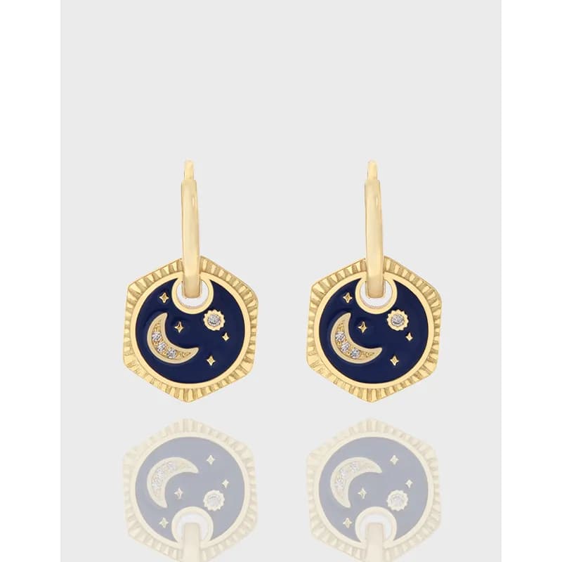 Gold-tone drop earrings with navy enamel moon and star motif and crystal accents on a hexagonal frame.