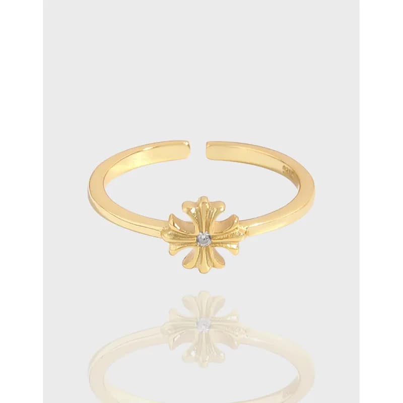 Open-ended polished sterling silver ring with a raised flower motif and tiny central stone.