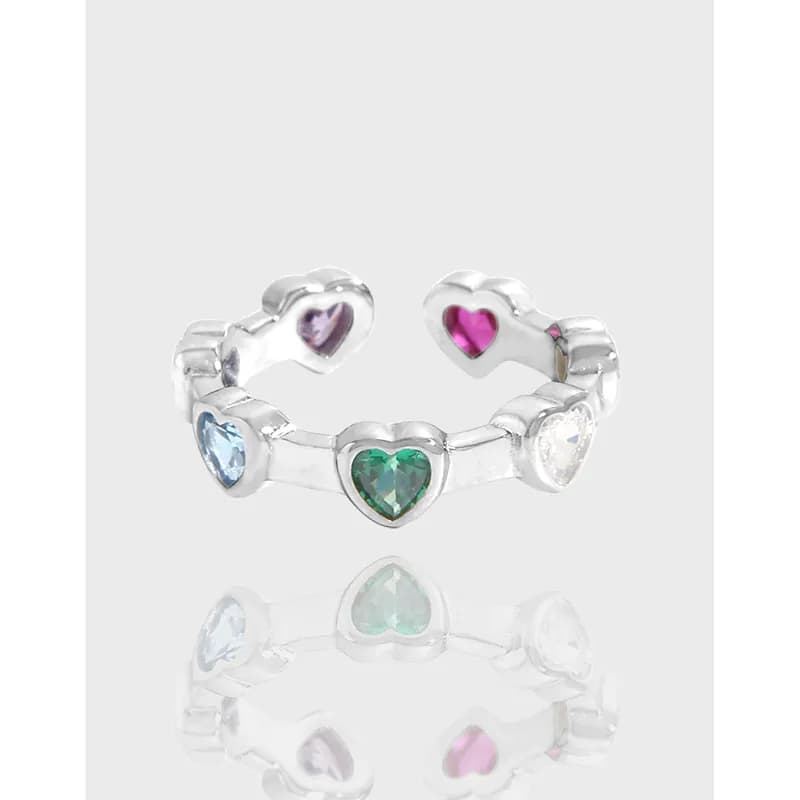 Open silver ring with a row of colorful heart-shaped stones along the band.