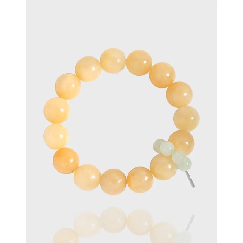 Polished sterling silver bead bracelet with peach beads and a small pale-green accent near the clasp.