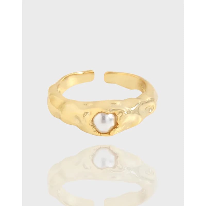 Polished sterling silver ring with an irregular textured band and a small heart-shaped pearl centerpiece.