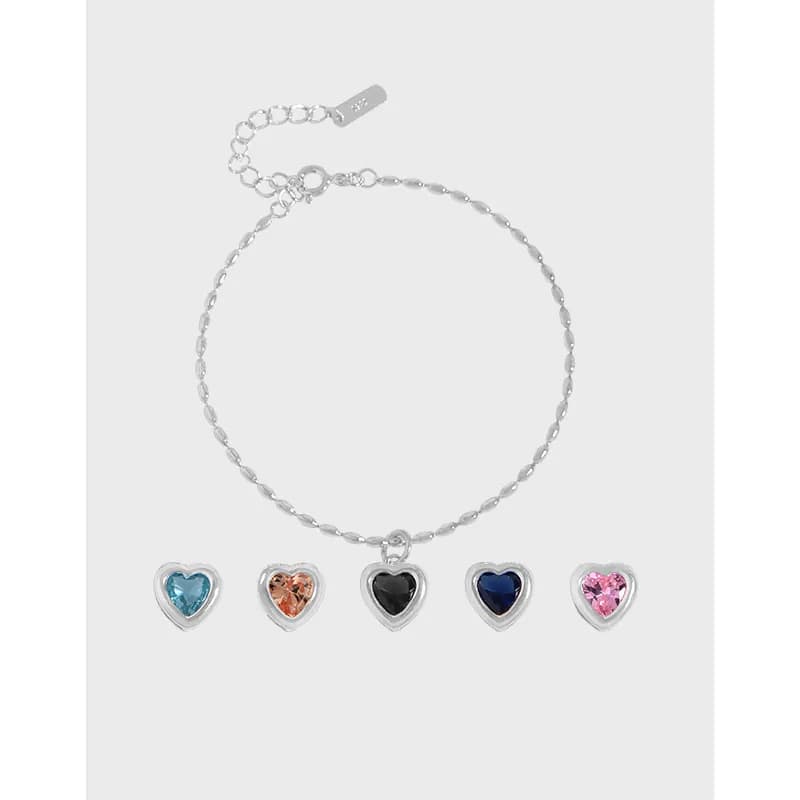 Delicate sterling silver bracelet with five enamel-heart charms hanging along the chain.
