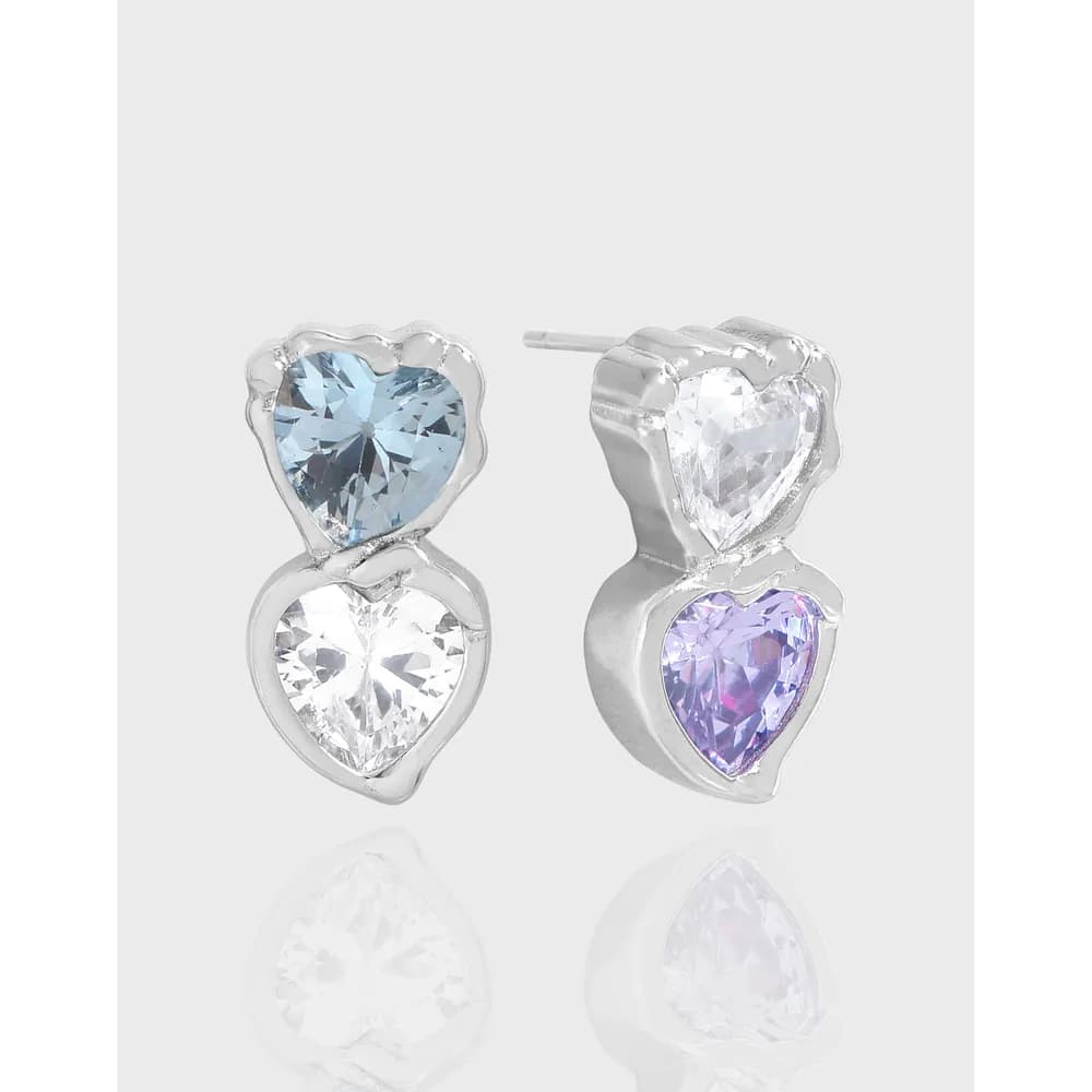Pair of two-tone heart-shaped gemstone earrings in polished silver, with each ear ornament showing stacked hearts and colored stones.