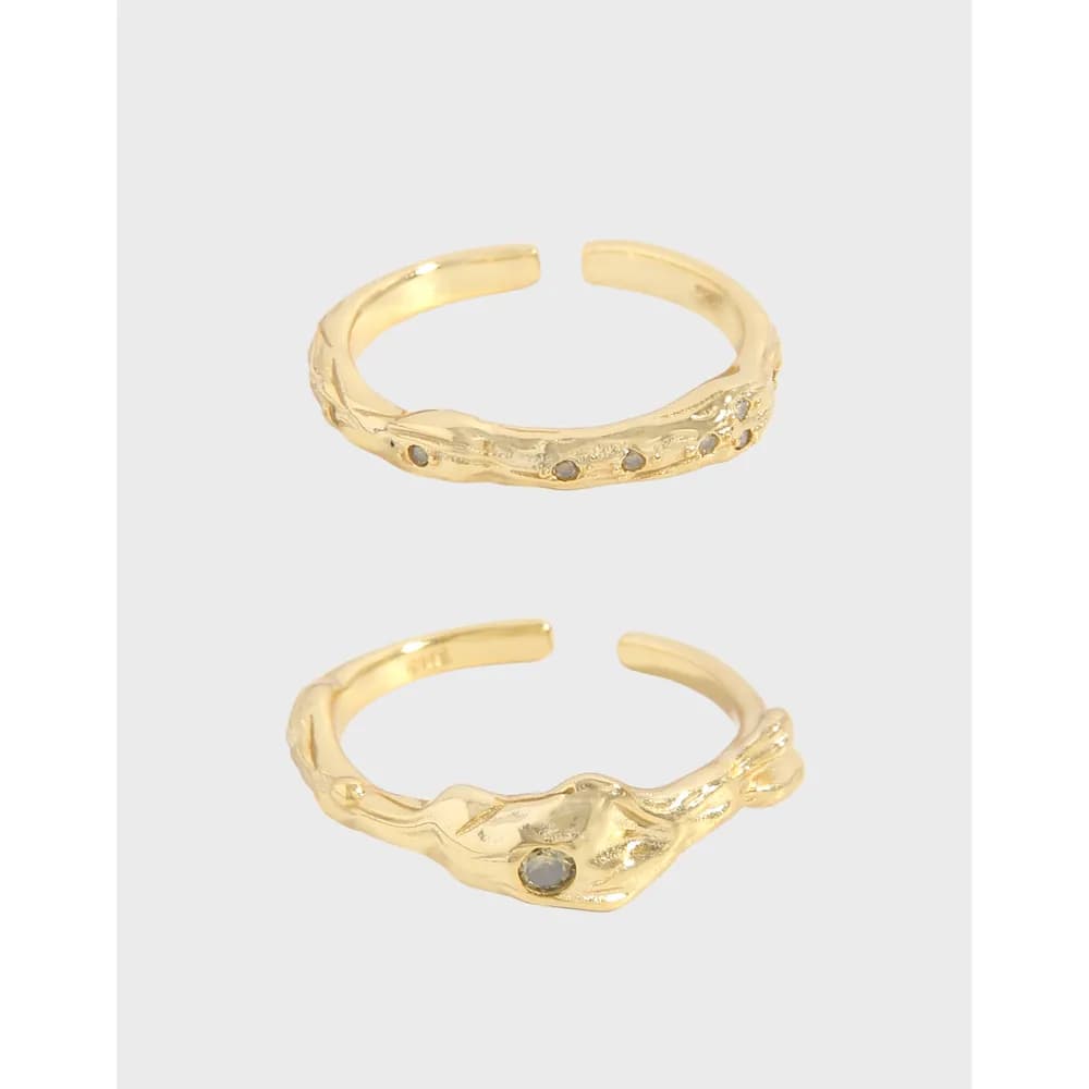 Two open adjustable sterling silver rings with a textured vine motif and small stone accents on a light gray background.