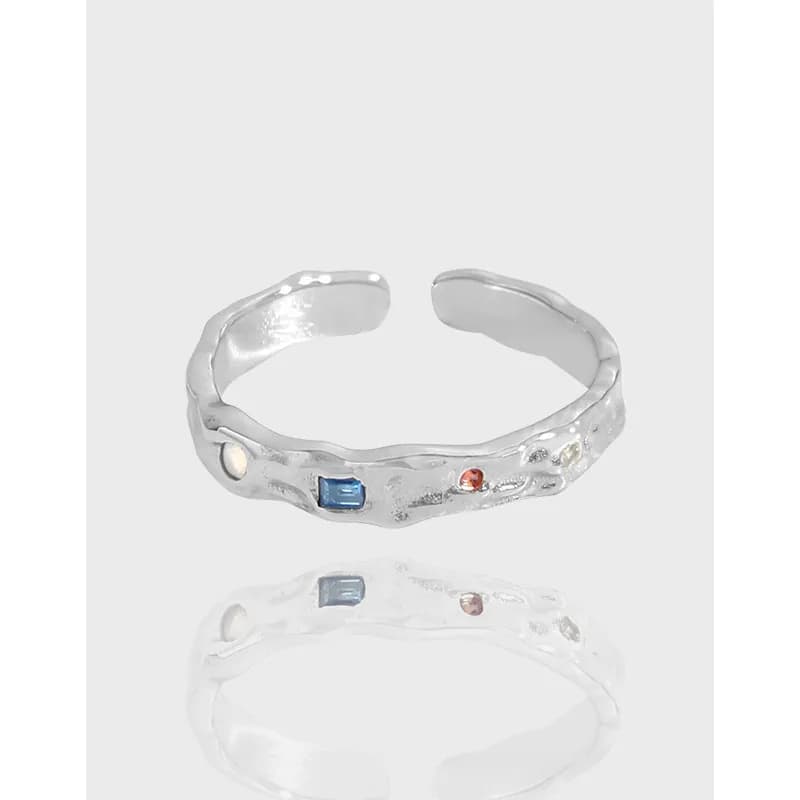 Polished textured silver ring with three small colored stones set along the band.