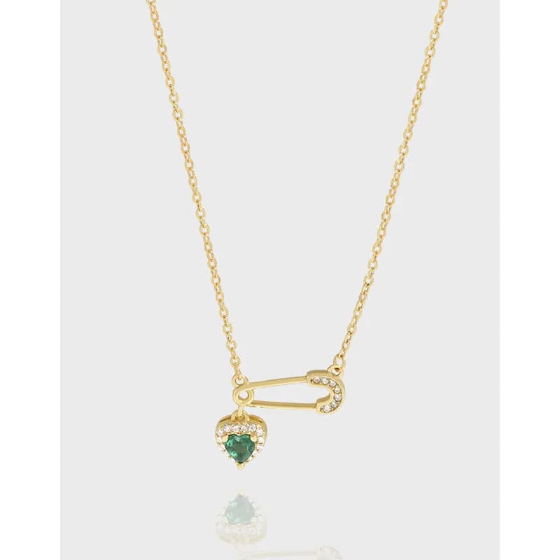 Polished sterling silver necklace with a safety-pin charm and a heart emerald pendant on a delicate chain.