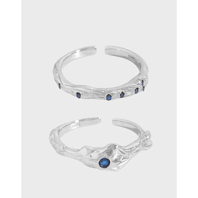 Open-ended sterling silver ring with a textured wave design and blue gemstones along the band.