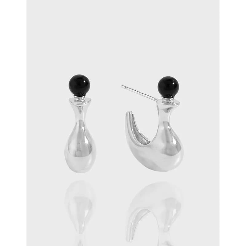 Polished sterling silver drop earrings with black bead accents on a pale background.
