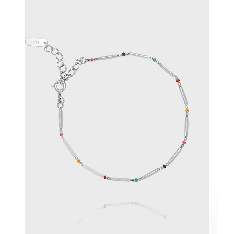 Polished sterling silver bracelet with cylinder beads and multicolored accents laid flat on a light background.