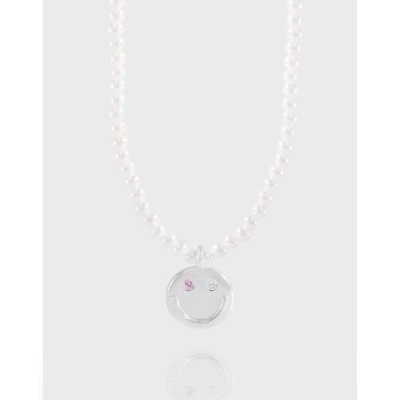 Pearl bead necklace with a circular silver smile pendant hanging at the center.