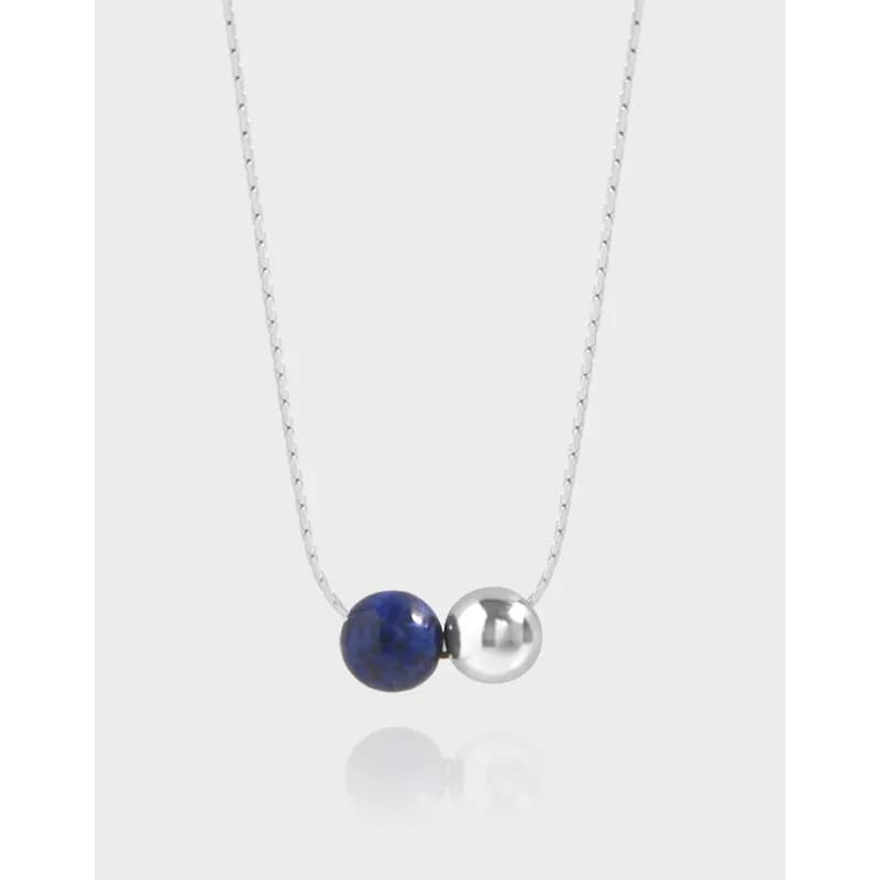 Sterling silver necklace with a blue lapis bead and a silver bead pendant centered on a delicate chain.