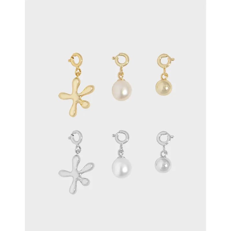 A delicate necklace with a starburst charm and two pearl drop charms on small hoops, shown in gold and silver tones.