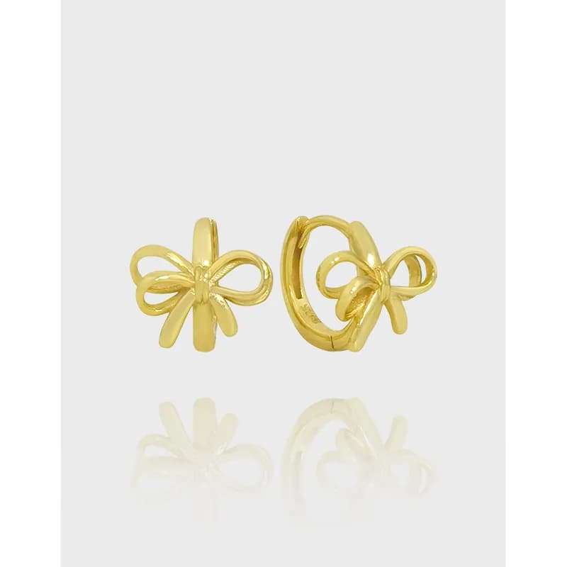 Polished bow-shaped earrings with small hoops on a light background.