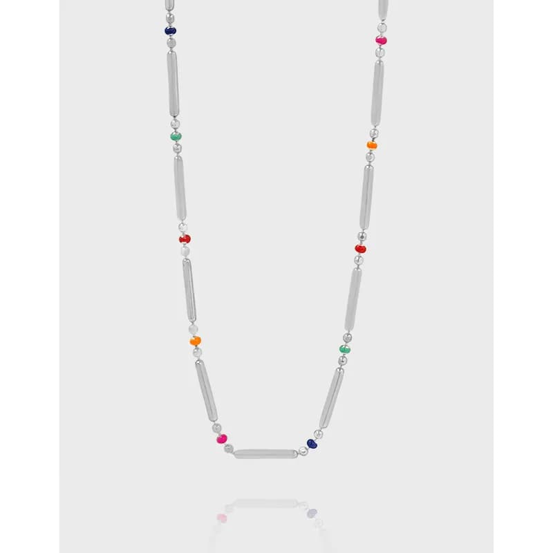 A polished sterling silver necklace with rectangular bar segments and multicolored beads hangs against a light background.