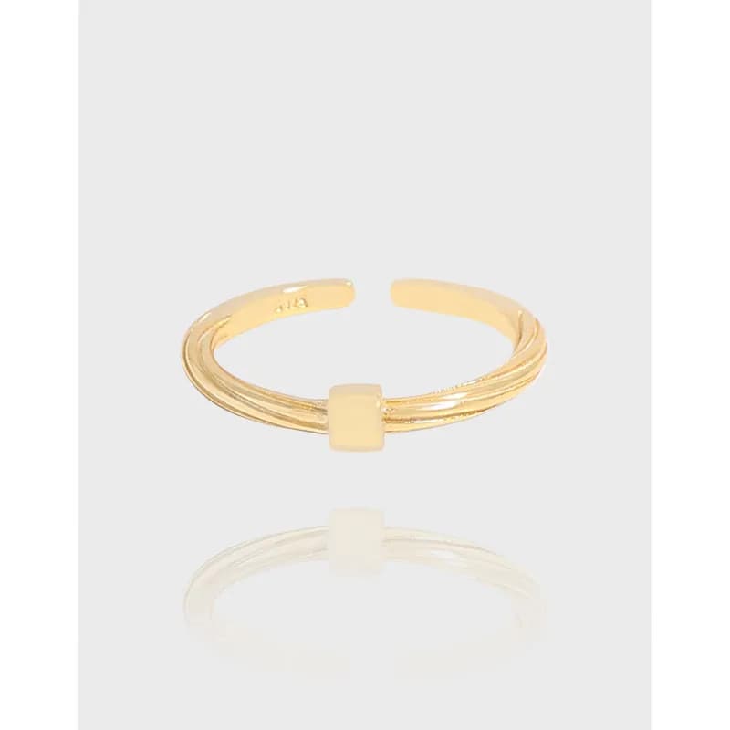 Open adjustable ring with three slim bands and a central square bead on a polished surface.