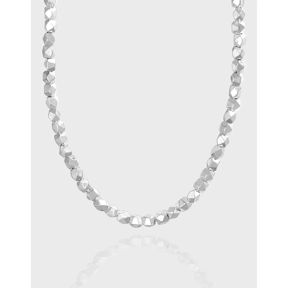 Polished sterling silver necklace with faceted cube beads on a simple background.