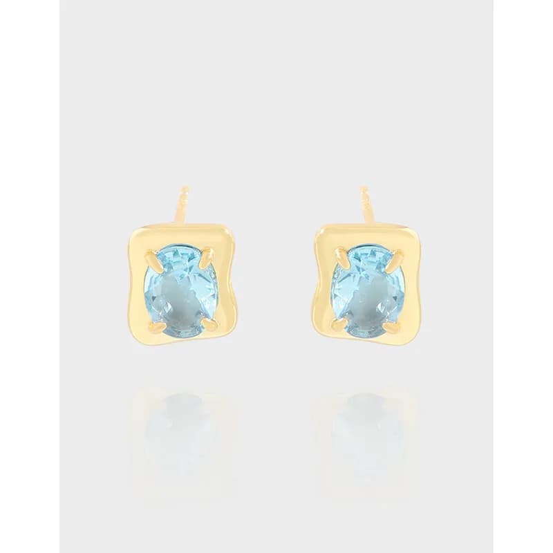 Gold-tone square framed earrings with light blue oval stones set in four-prong settings.
