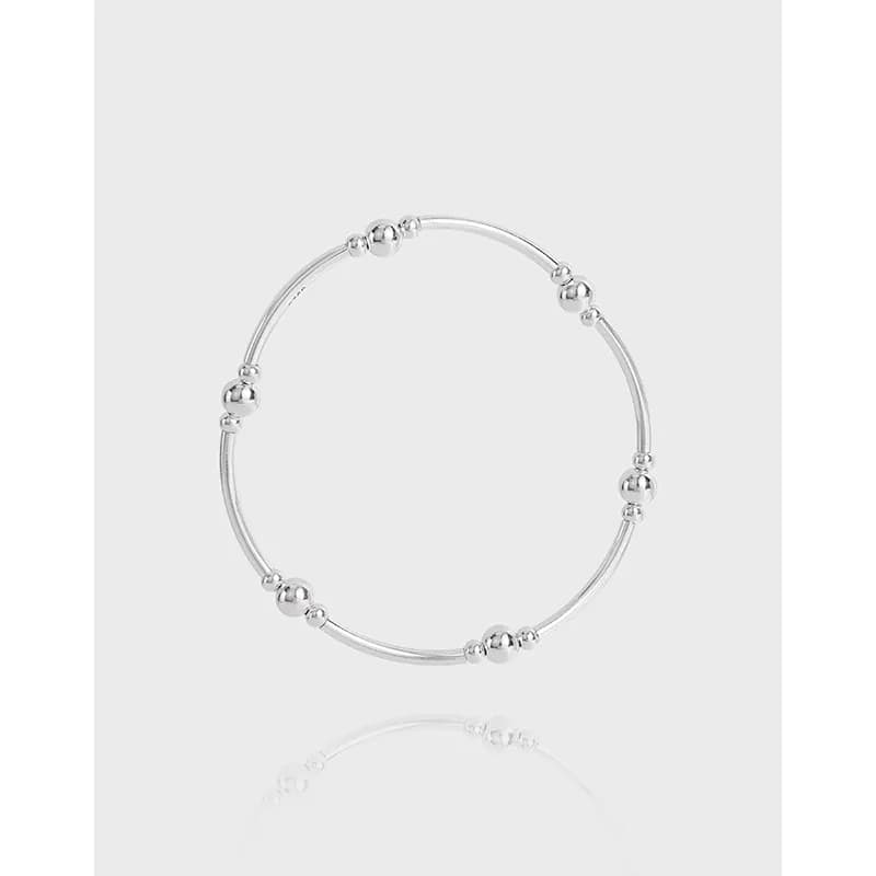 Polished sterling silver beaded hoop bracelet on a light gray backdrop.