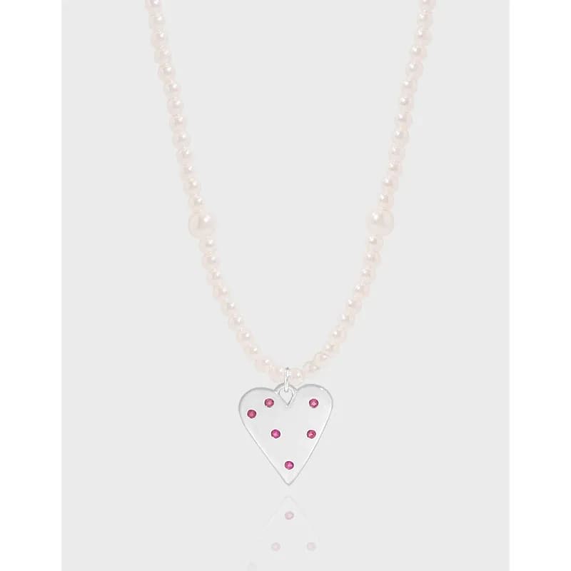 Pearl bead necklace with a polished silver heart pendant accented by pink stones.