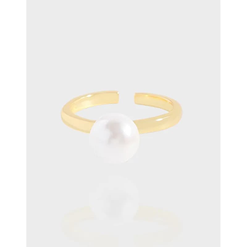 Polished sterling silver open-ring with a white pearl centerpiece on a light background.