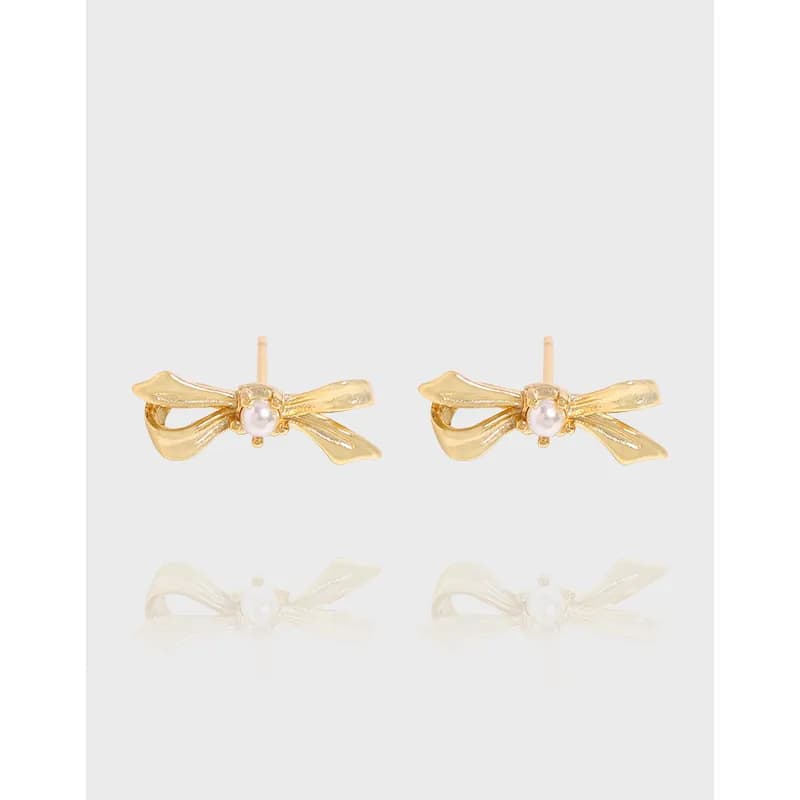 Pair of polished silver bow-shaped stud earrings with central pearls on a light background.