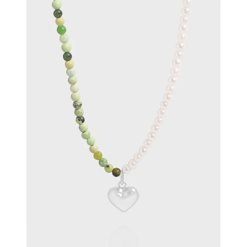 Beaded necklace with green stones on one side and white pearls on the other, featuring a silver heart pendant