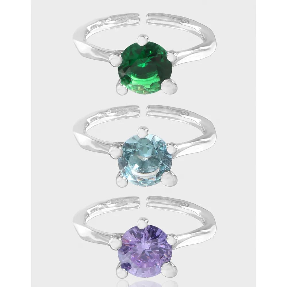 Three polished sterling silver rings, each with a round colored gemstone held by four prongs
