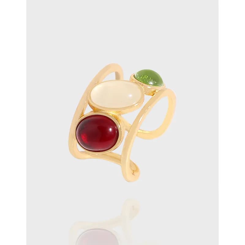Polished sterling silver ring with three bezel-set cabochons in red, white, and green on a curved band.