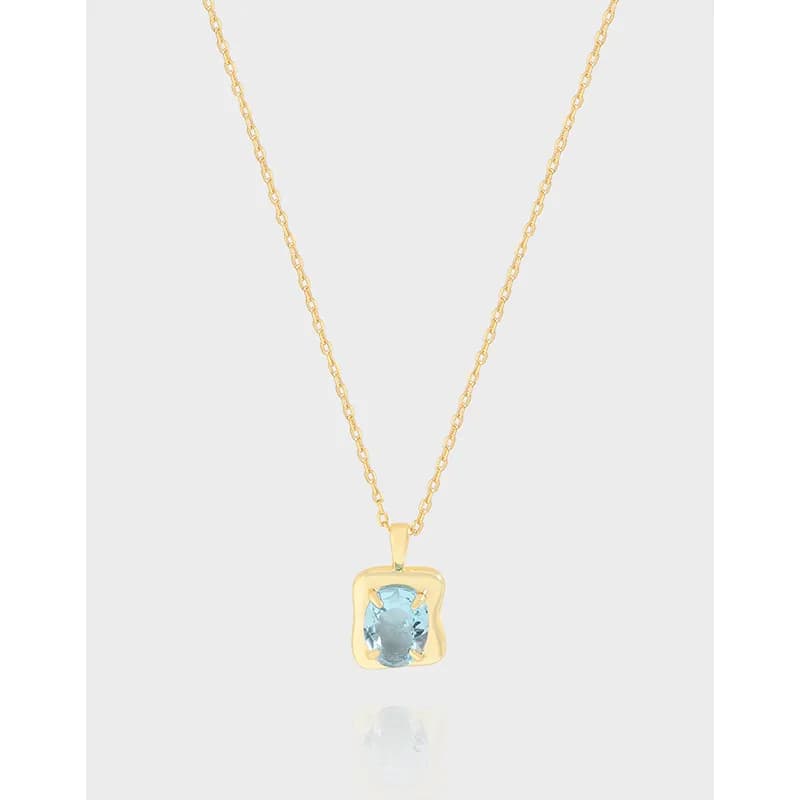 Delicate sterling silver necklace with a square bezel pendant housing a pale blue gemstone.
