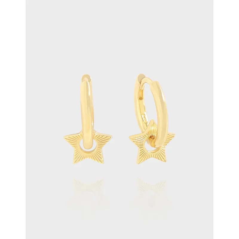 Close-up of polished sterling silver hoop earrings with a dangling textured star charm.