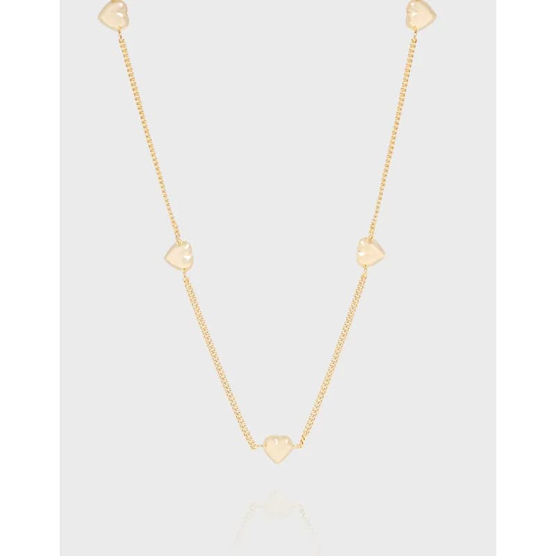 Delicate polished silver necklace with small heart charms along the chain and a central larger heart pendant.