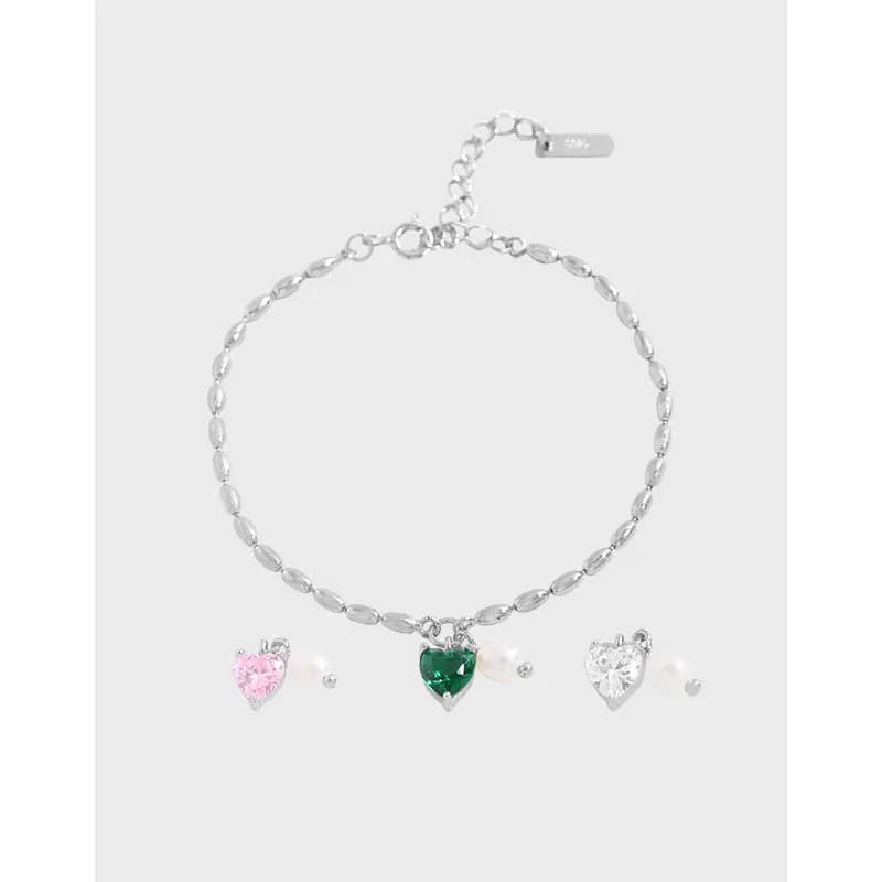 Polished sterling silver bracelet with three heart charms and pearl accents hanging along the chain.