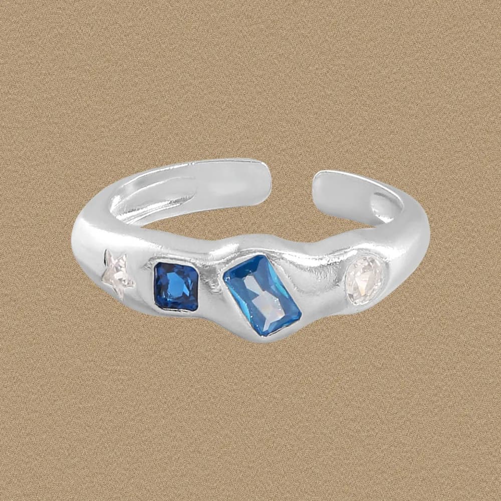 Polished sterling silver ring with three gemstone-like accents set along a wavy band.