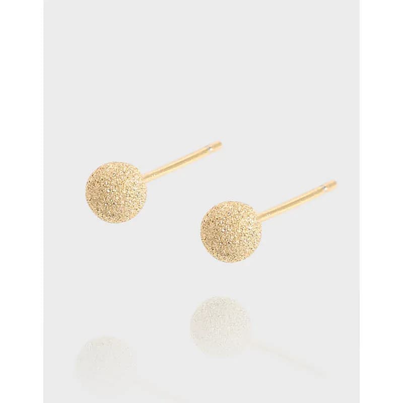 Pair of textured ball stud earrings on their posts against a light background
