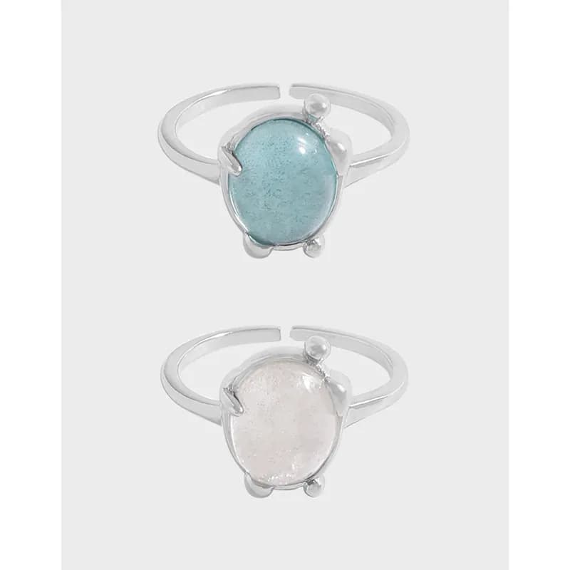 Two sterling silver rings featuring oval enamel cabochons in blue and white on a light background.