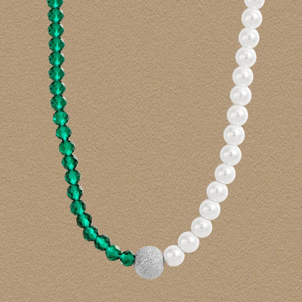 Two-tone emerald and pearl necklace with a textured pavé accent bead on a gold background.