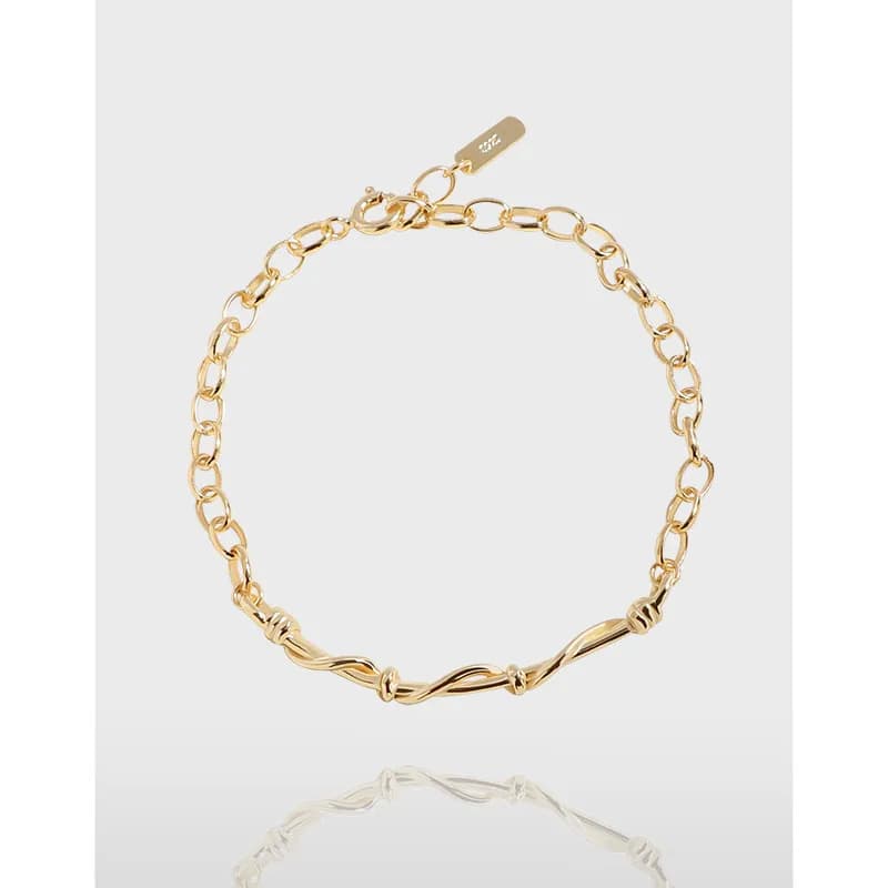 Polished chain bracelet with a twisted center motif and a small clasp on a light background.
