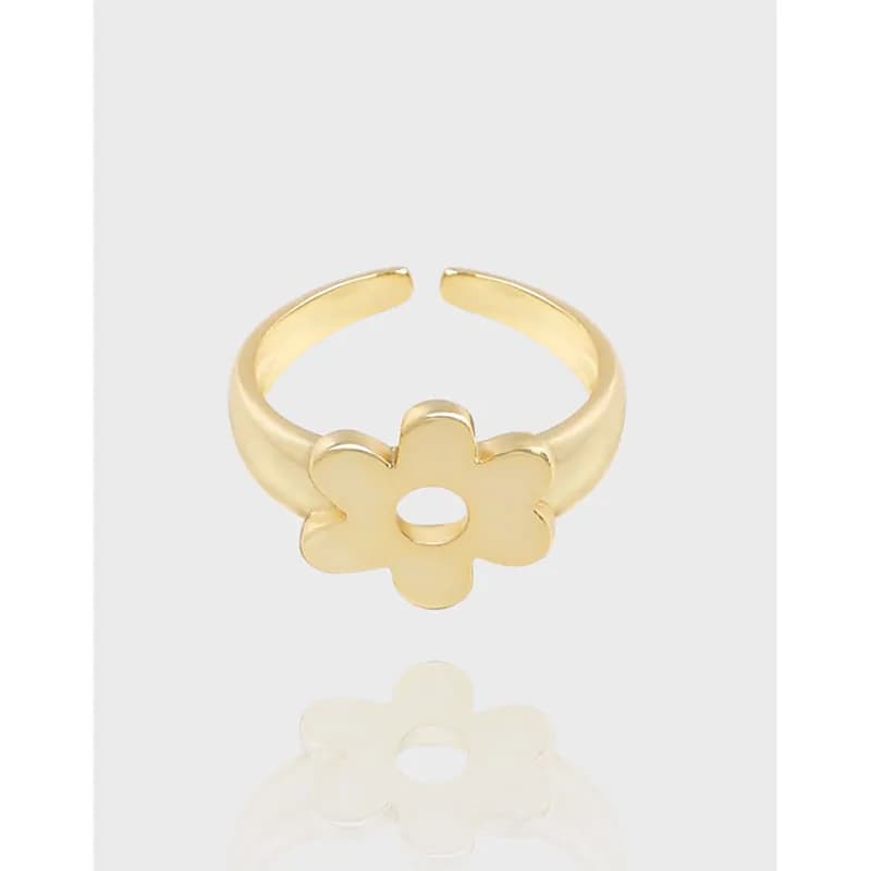 Gold-toned flower ring with a five-petal blossom and circular center cutout on a pale background.