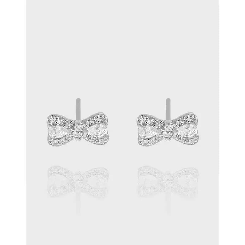 Pair of polished sterling silver bow-shaped pavé earrings on a light background.