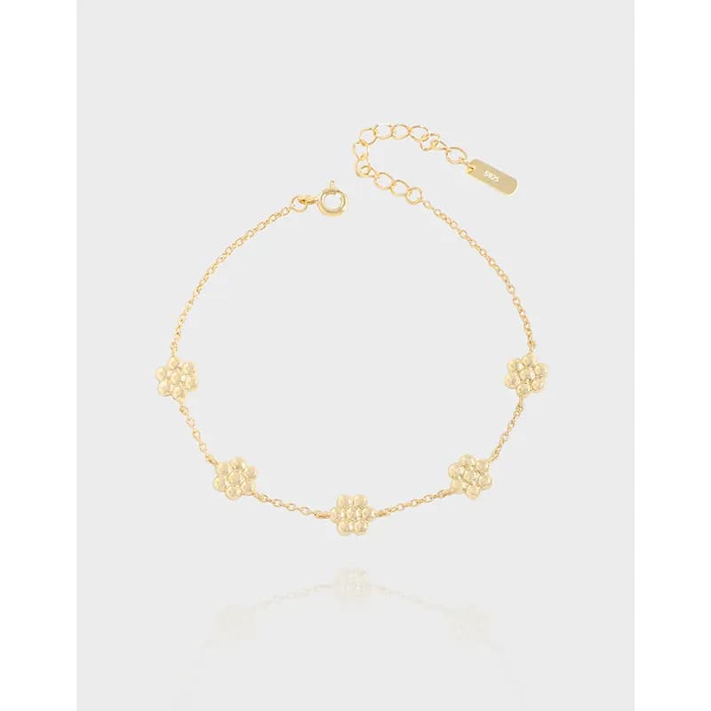 Delicate sterling silver bracelet with small flower charms along a fine chain and adjustable extender