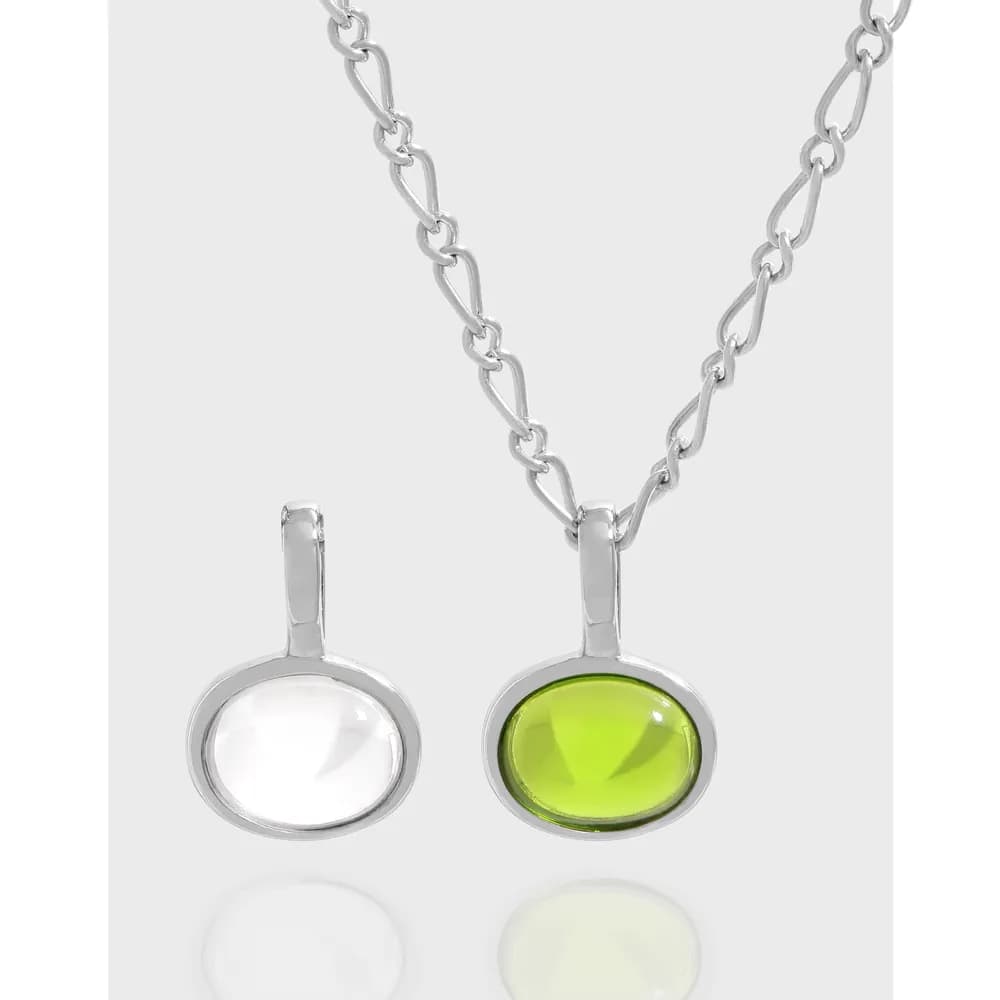 Two oval bezel-set pendants in sterling silver on a chain, one white and one neon lime stone.