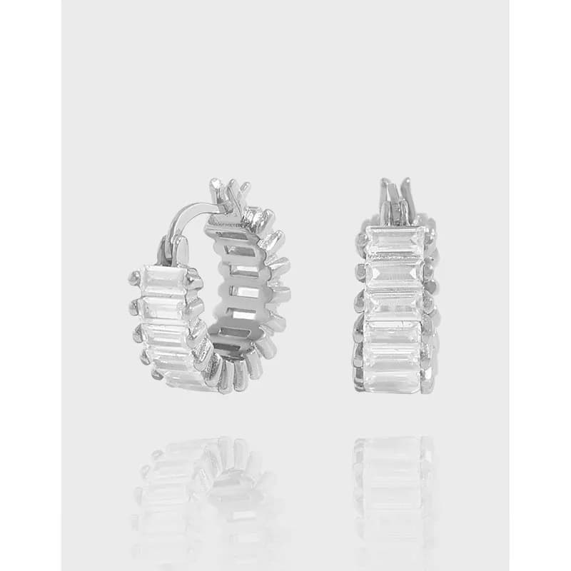 Polished sterling silver hoop earrings with baguette-cut stones on a light background.