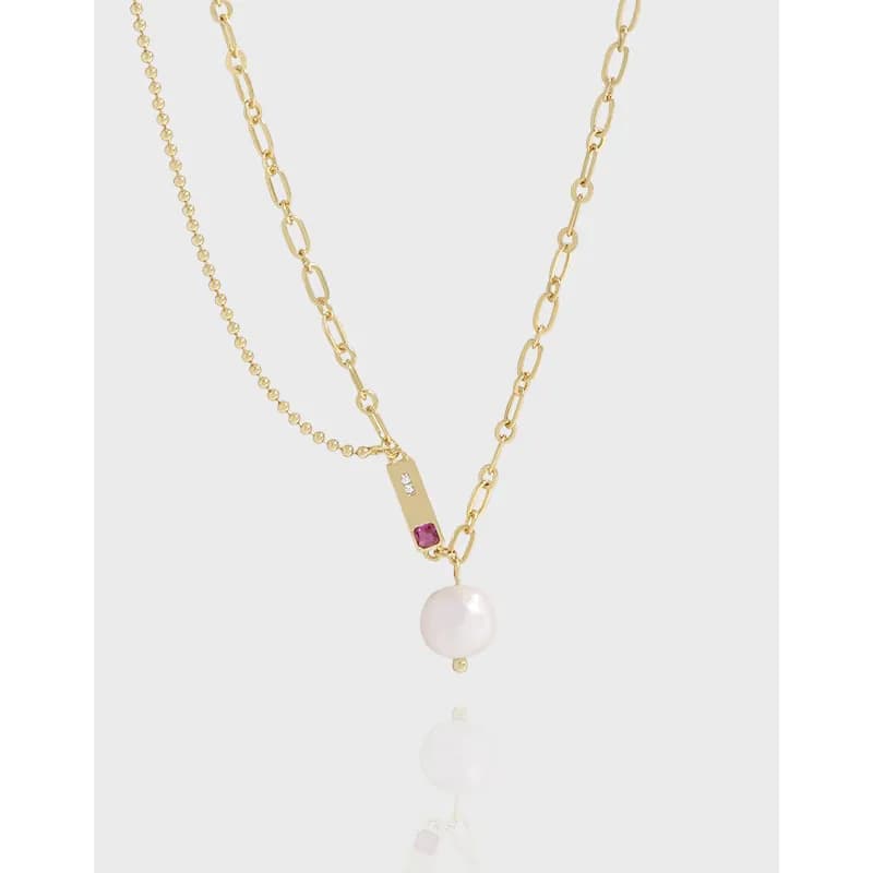 Layered necklace with a beaded chain and a link chain, featuring a bar pendant and a hanging pearl.