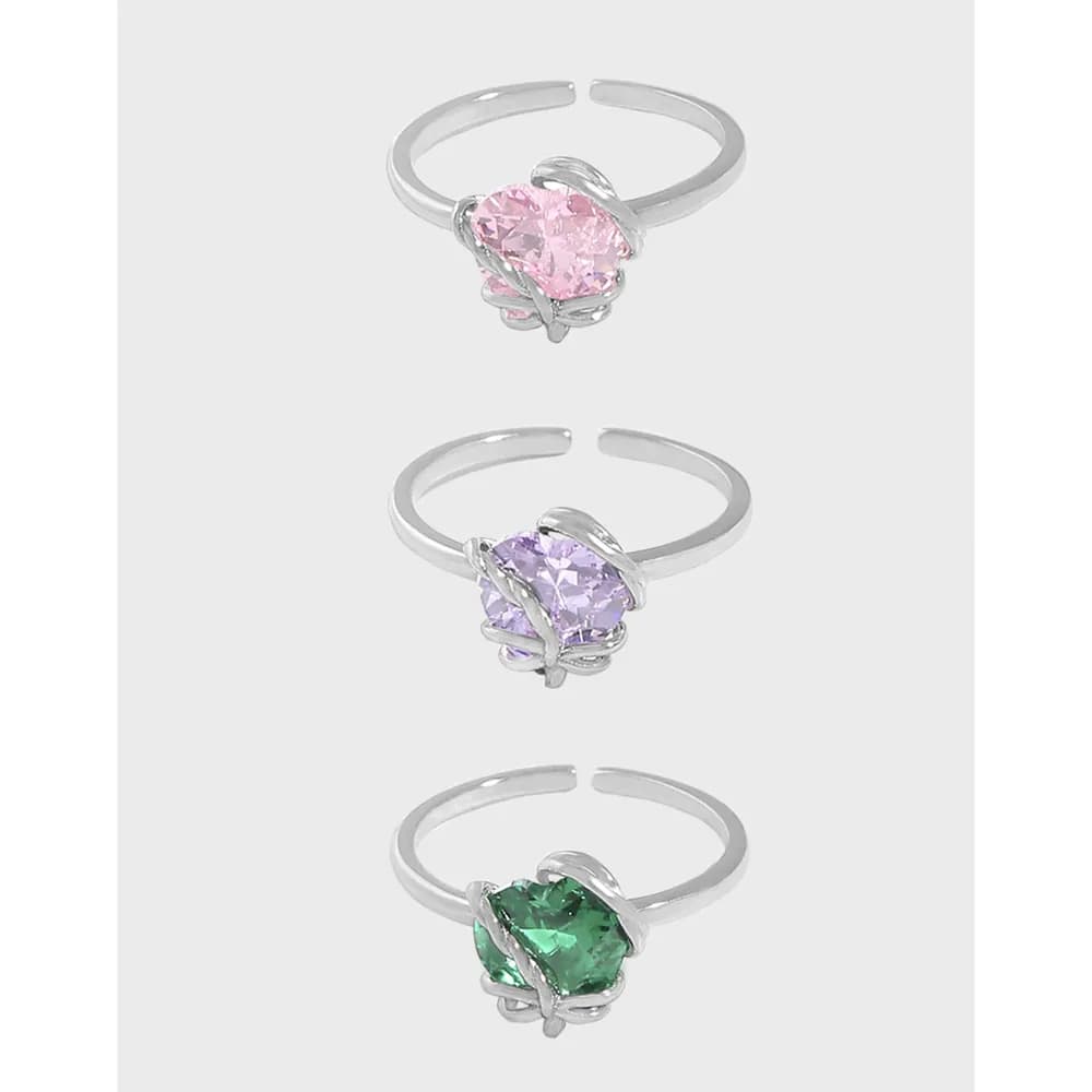 Three sterling silver rings with pastel faceted stones wrapped by a vine-like metal setting and polished bands.