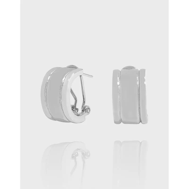 Close-up of polished sterling silver hoop earrings with two parallel bands and hinged back
