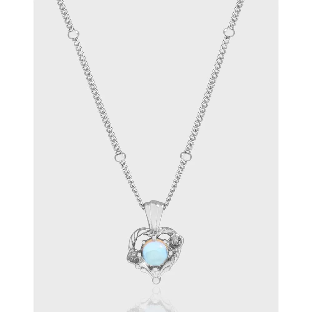 Polished sterling silver necklace with an ornate filigree pendant featuring a pale blue cabochon centerpiece.