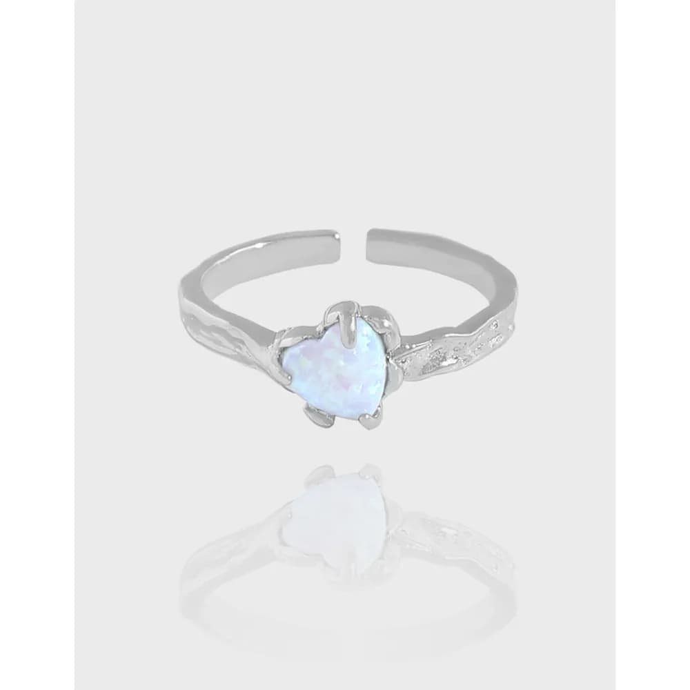 A polished sterling silver ring with a heart-shaped opal centerpiece and subtle engraving along the band.