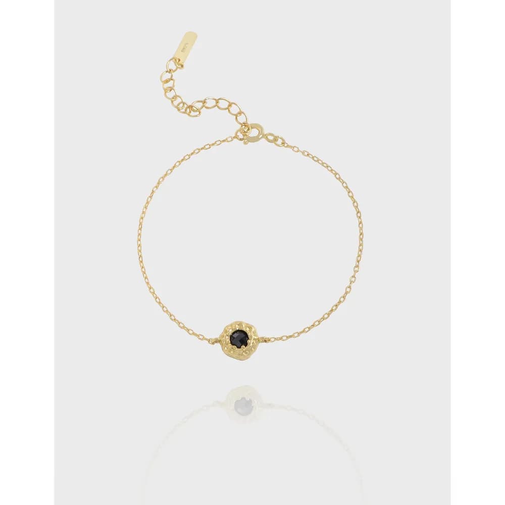 Delicate sterling silver bracelet with a textured circular bezel setting and dark central stone
