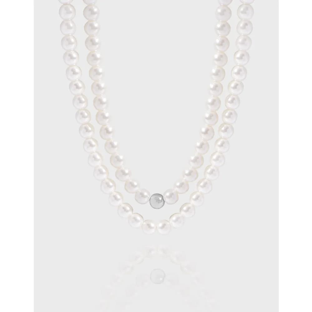 Two strands of white pearls arranged in a V-shape with a small silver bead at the center