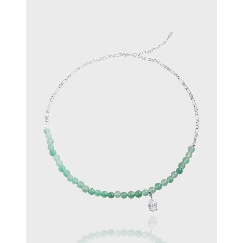 Silver chain necklace with mint-green beads and a teardrop pendant on a light background.